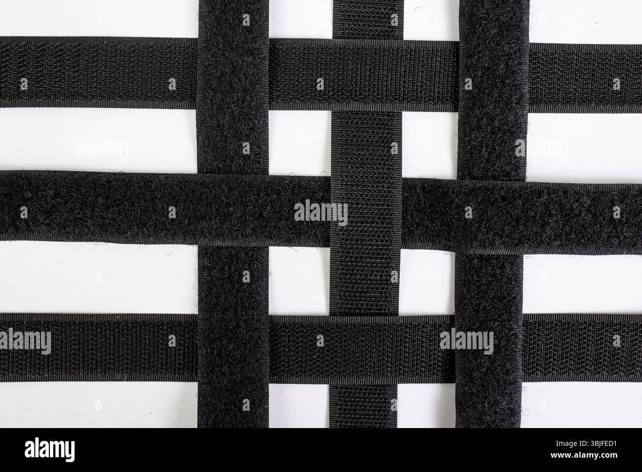 Bandes adhésives Velcro paires de bandes se chevauchant dans un motif de grille, isolé sur fond blanc, gros plan Banque D'Images