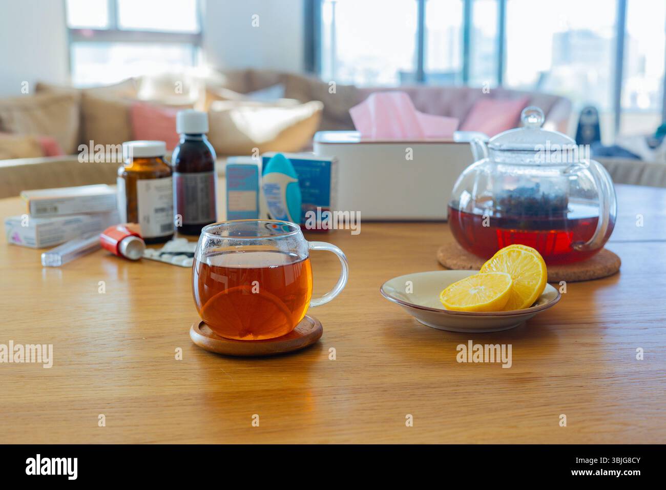 Gros plan d'une tasse de thé au citron sur une table en bois, théière, pilules et médicaments à proximité, symbole de santé, de récupération et de traitement du froid à la maison Banque D'Images