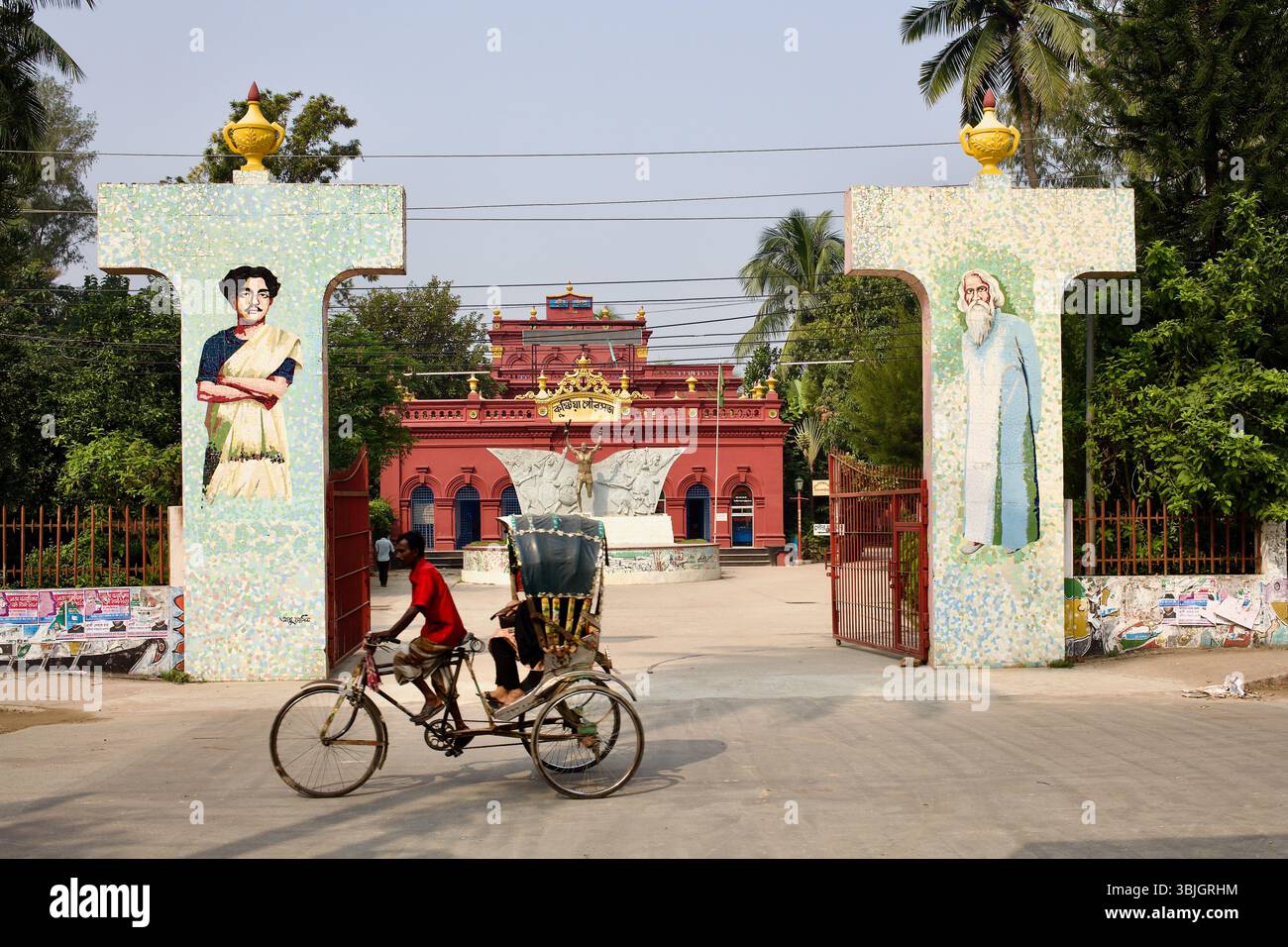 Un pousse-pousse passe devant la porte en mosaïque de Kushtia Paur Bhavan, l’ancienne maison zamindar devenue bureau municipal depuis 1966 à Kushtia, au Bangladesh. Banque D'Images