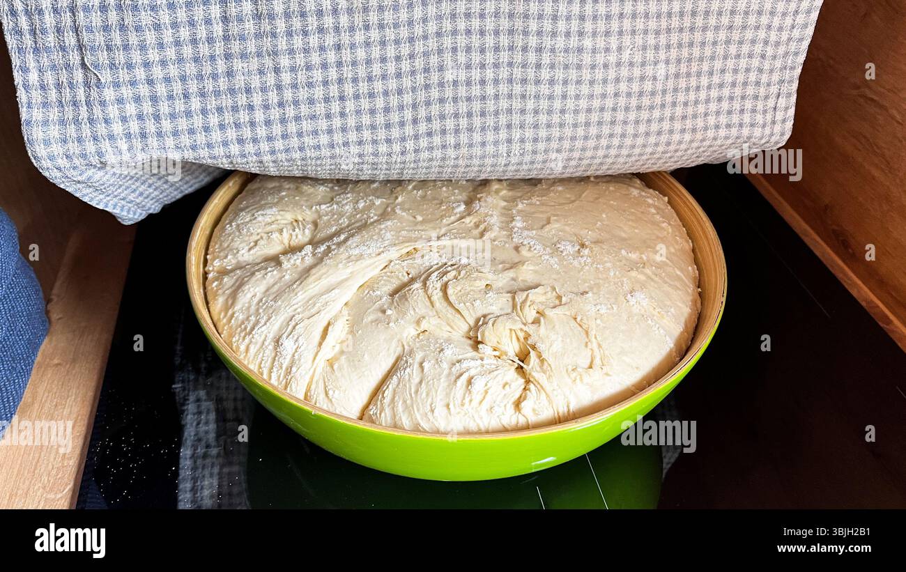 Pâte de levure fraîche parfaitement faite dans un bol pour le pain ou le gâteau reposant sous la tour de coton. Pâte de levure crue reposant et levant pour la cuisson. Fait maison Banque D'Images