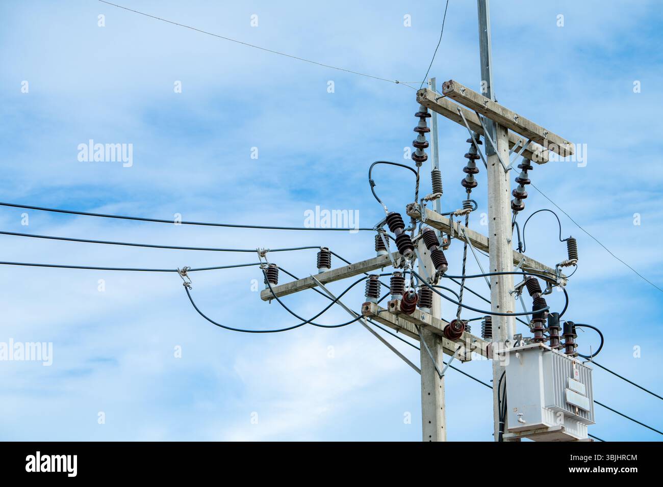 Équipement de poteau de service électrique comprenant des câbles de transmission d'énergie et des isolants contre le ciel bleu démontrant la technologie d'infrastructure énergétique Banque D'Images