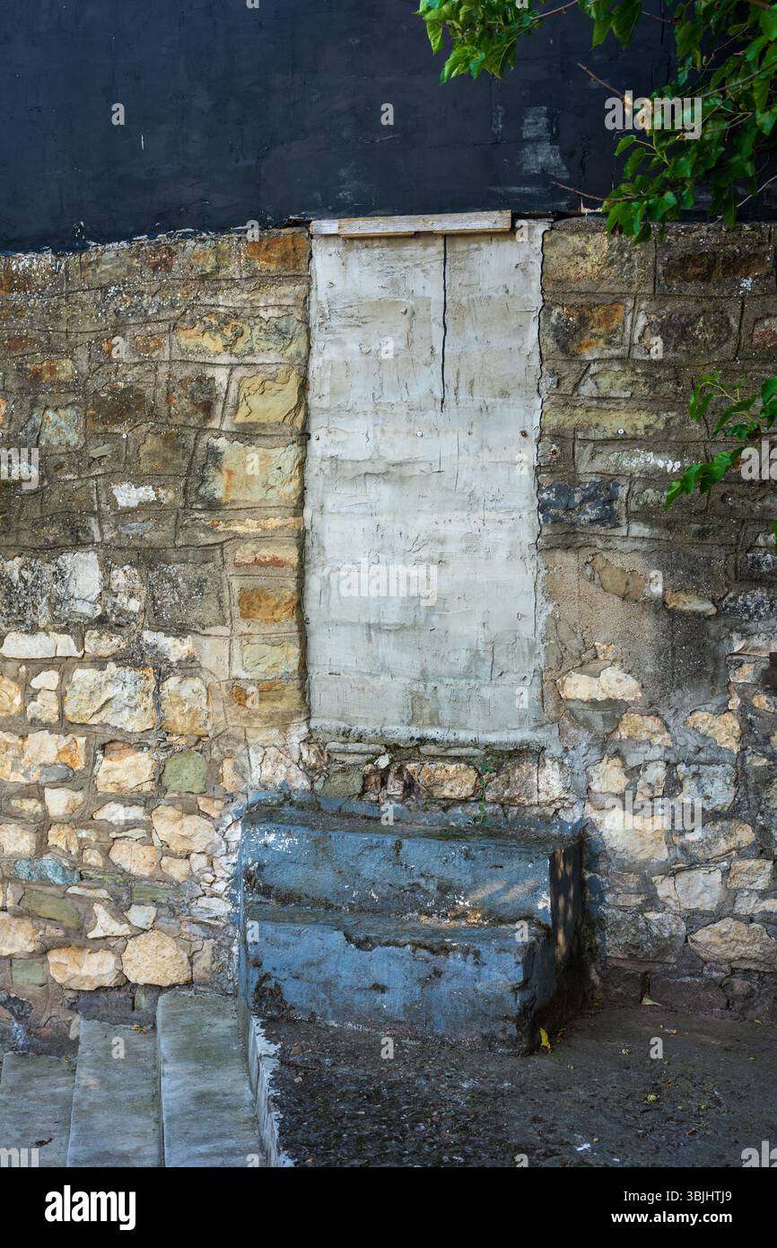 Porte en briques avec marches en béton. Fond de mur de pierre. Banque D'Images
