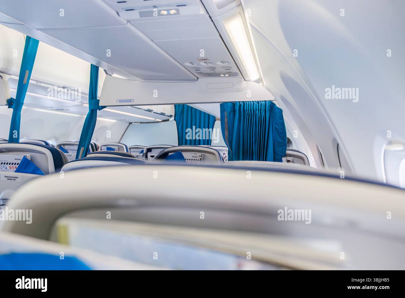 Intérieur lumineux de cabine d'avion avec rideaux bleus et sièges vides. Aviation commerciale, conception d'avions modernes, environnement de voyage, prêt pour le vol Banque D'Images