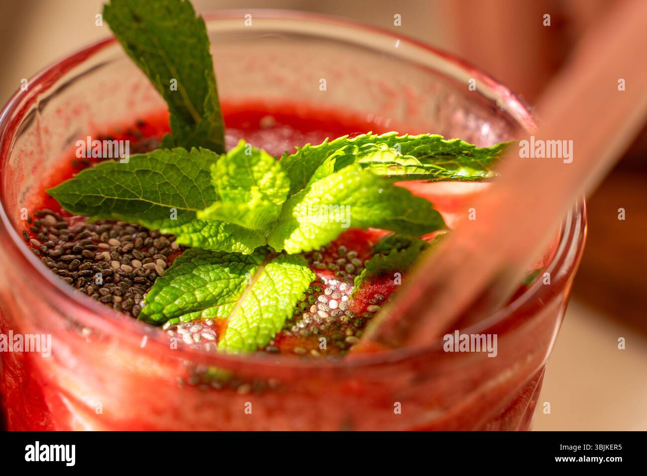 Gros plan de smoothie à la fraise avec des graines de chia et des feuilles de menthe fraîche en verre pour une alimentation végétalienne saine Banque D'Images