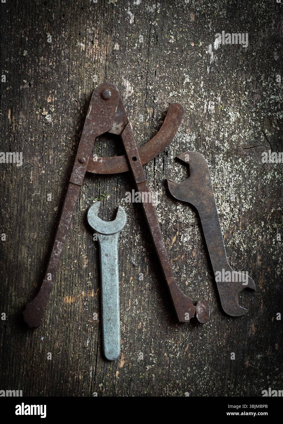 Une collection d'outils vintage, y compris un étrier et plusieurs clés, repose sur une surface en bois rustique Banque D'Images