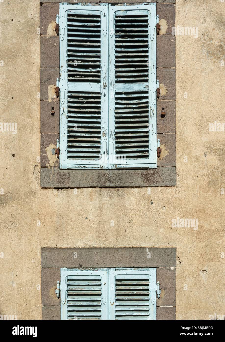Deux ensembles de volets bleus vintage ajoutent du charme à un mur altéré, France Banque D'Images