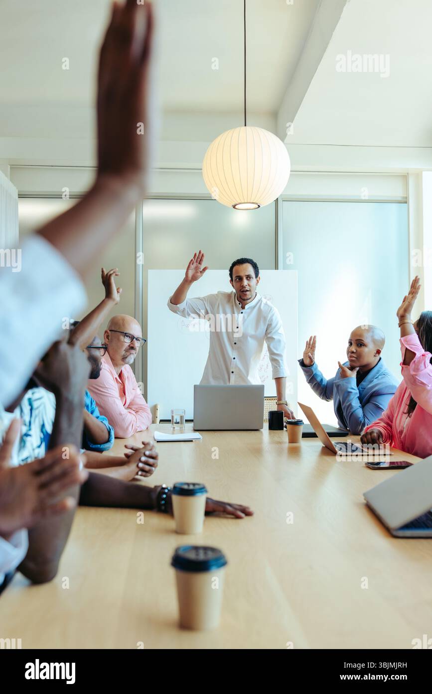 Un groupe de professionnels divers dans une salle de conférence moderne est engagé dans une réunion d'affaires. Les membres de l'équipe lèvent la main pour voter, illustrat Banque D'Images