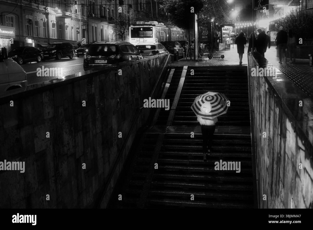 Homme sous la pluie marchant avec un parapluie. Personne méconnaissable en flou de mouvement. Banque D'Images