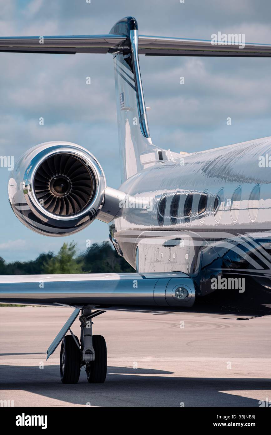 Vue arrière verticale d'un jet d'affaires de luxe avec fuselage poli, turboréacteur et queue en T. Tourné sur la rampe d'accès de l'aéroport sous un ciel partiellement nuageux. Banque D'Images