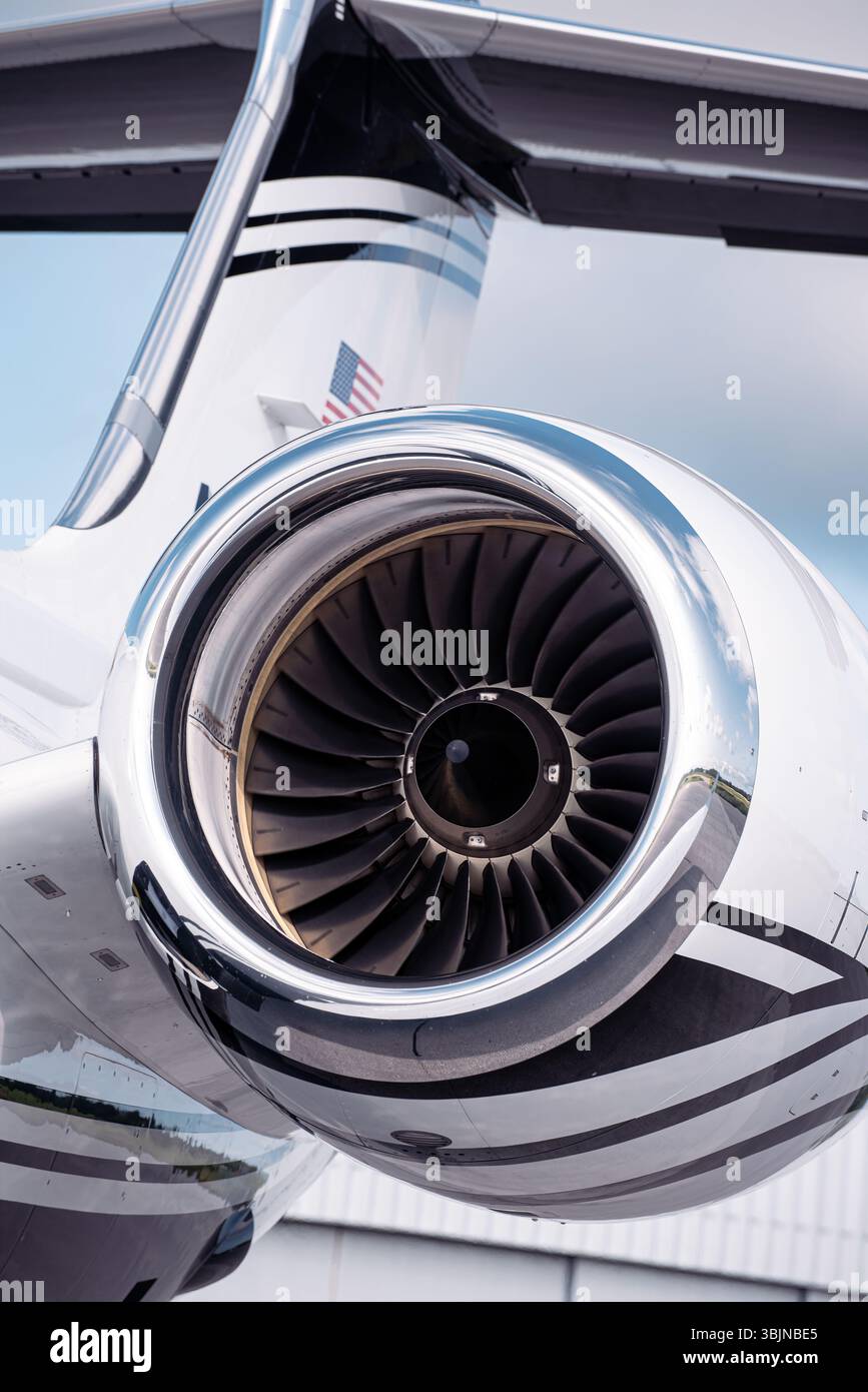 Gros plan d'un moteur à réaction sur un avion d'affaires de luxe avec queue en T, photographié sous un ciel lumineux. Pales de turboréacteur et nacelle polie dans les détails nets. Banque D'Images
