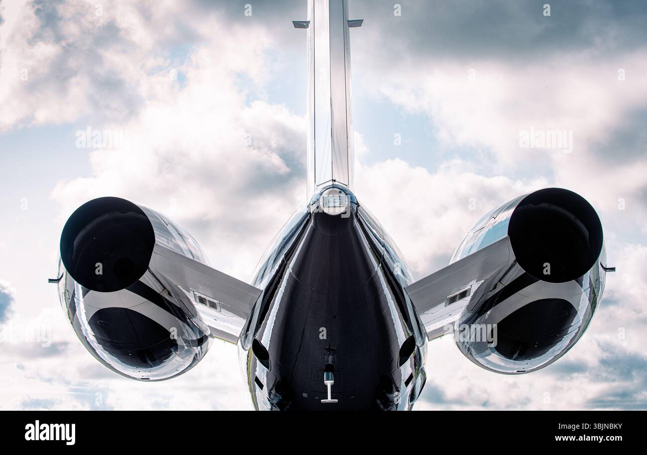 Vue arrière d'un jet privé de luxe avec deux moteurs et conception en T-tail, photographié du niveau du sol regardant vers le haut contre un ciel nuageux spectaculaire. Banque D'Images