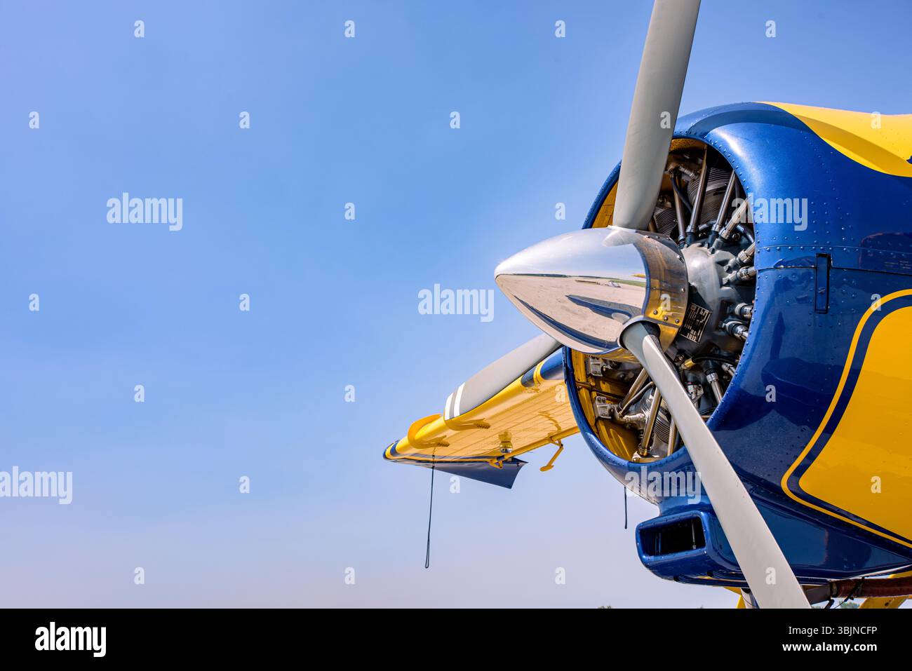 Gros plan du moteur radial et de l'hélice sur un avion jaune et bleu sous un ciel bleu clair. détails de l'avion avec des couleurs éclatantes et un style vintage. Banque D'Images