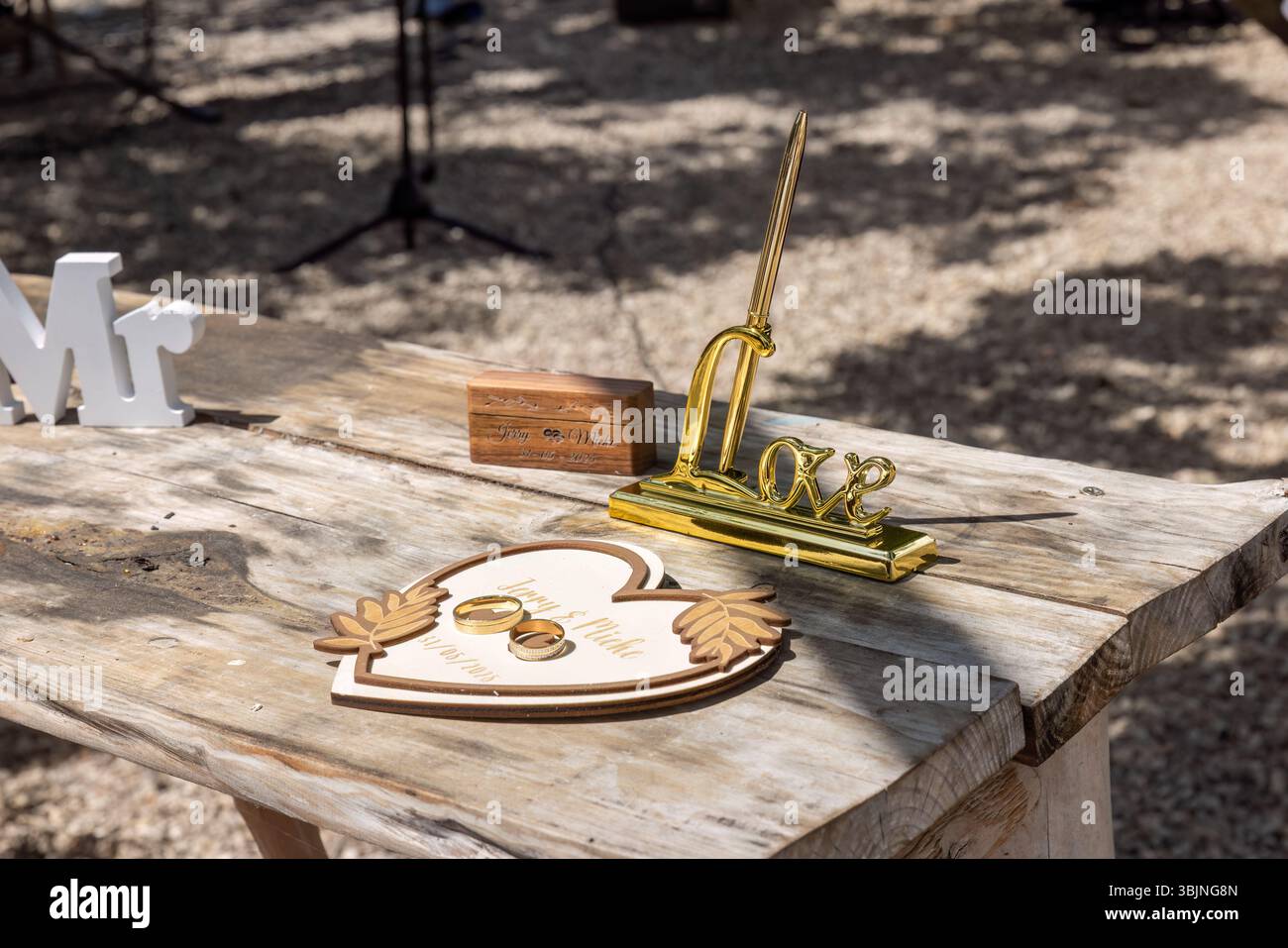 Belle table en bois rustique avec des anneaux de mariage, décor en forme de cœur et un ensemble de stylos dorés pour les vœux. Banque D'Images