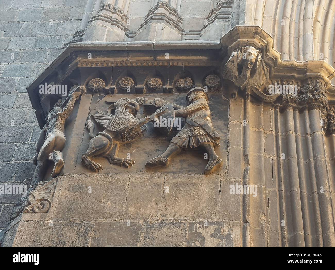 Barcelone, Espagne - 11 juillet 2024 : Barri Gotic, sculpture à la porte latérale dans Carrer dels Comtes de la cathédrale montre un soldat combattant un lion ailé avec drago Banque D'Images