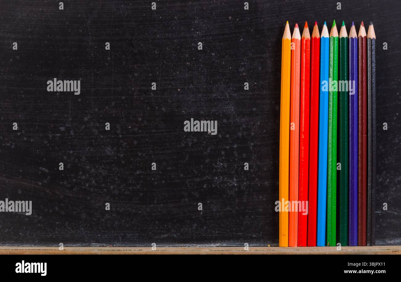 Crayons colorés contre tableau noir Banque D'Images