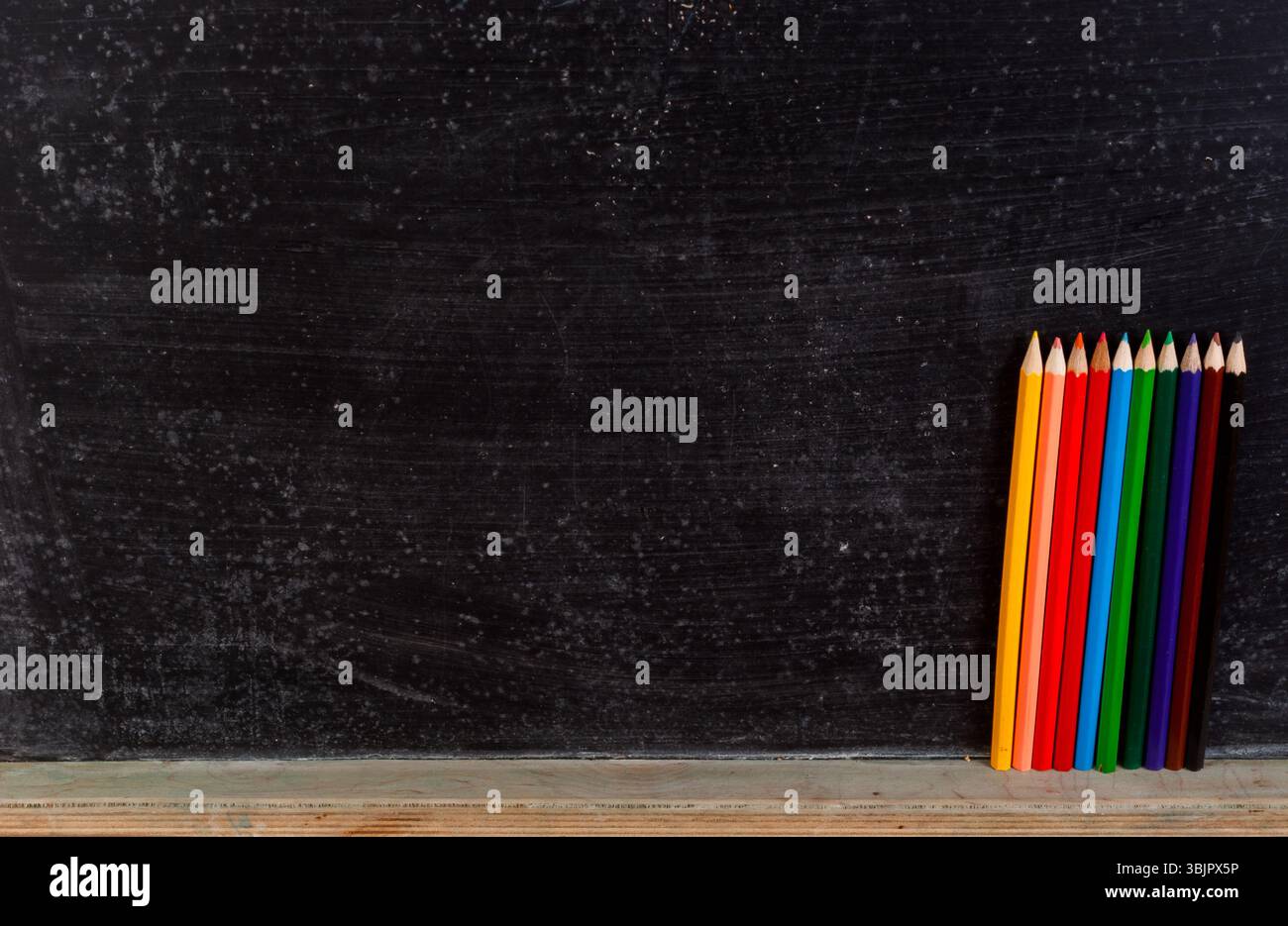 Crayons colorés contre tableau noir Banque D'Images