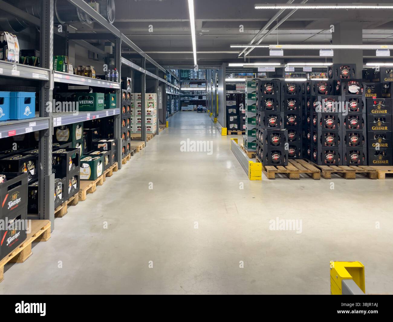 Allemagne Berlin 7 juin 2025. Une grande section de boissons dans un supermarché de style entrepôt avec des caisses de bière empilées sur des palettes. L'allée spacieuse est brick Banque D'Images
