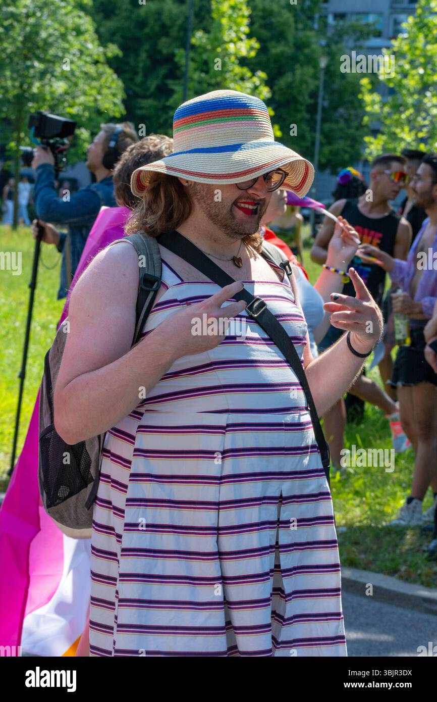 Un participant à la parade portant une robe rayée et un chapeau arc-en-ciel gestes lors de Varsovie Pride Parade à Varsovie, dans la Voïvodie masovienne, Pologne, en juin 2025. Banque D'Images