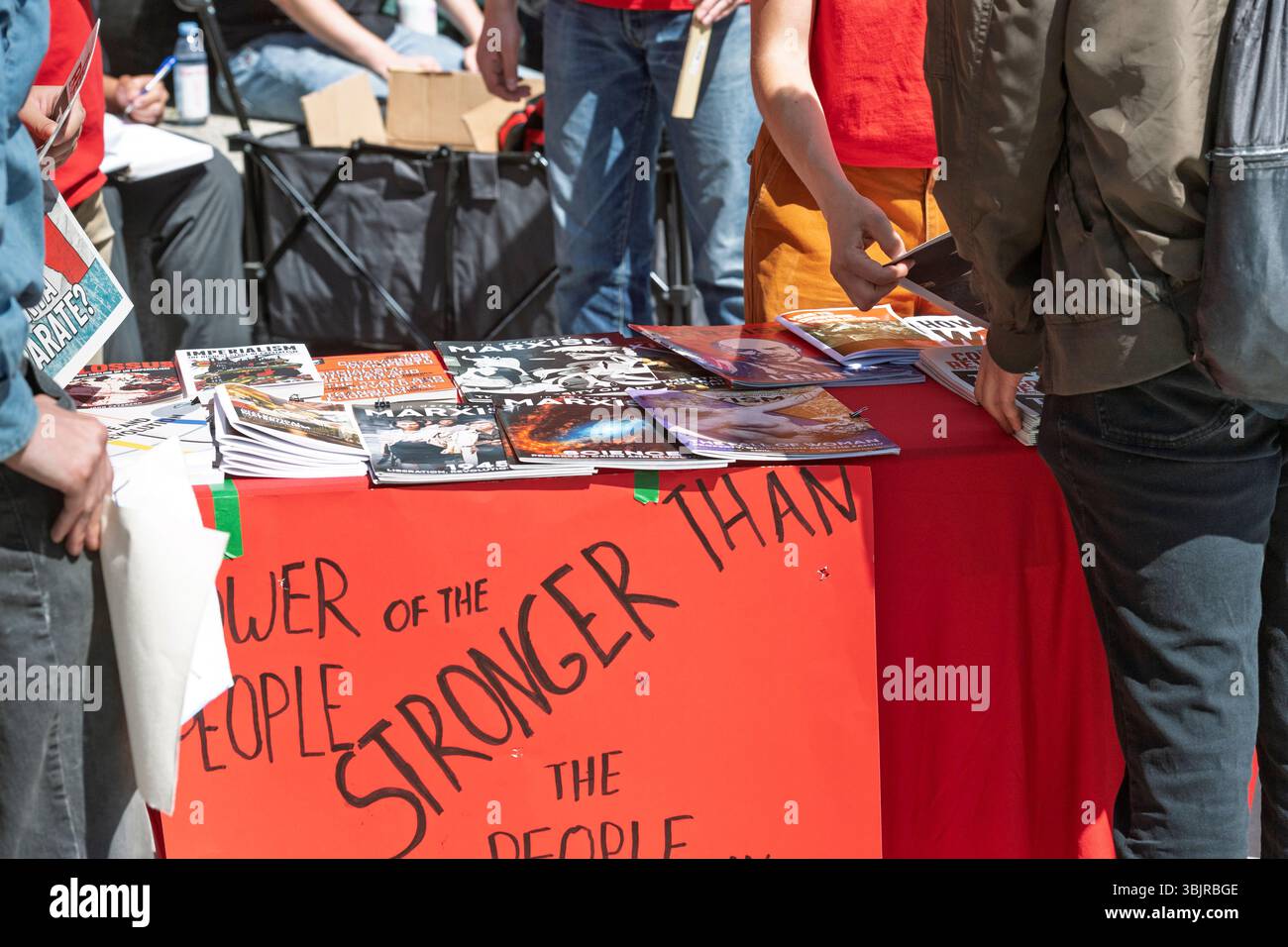 Les gens conversent autour d’une table avec des magazines marxistes et une pancarte lors d’une manifestation ou d’un rassemblement de rue du G7 véhiculant des thèmes d’unité et d’activisme Calgary Banque D'Images
