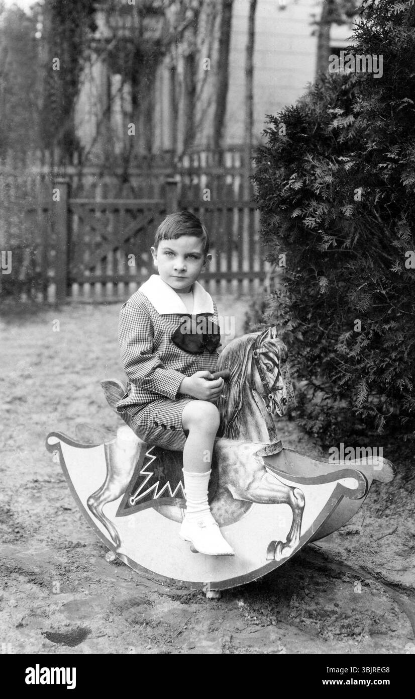 Garçon sur un cheval à bascule, années 1920, Un garçon assis dehors sur un cheval en bois, photo historique Banque D'Images