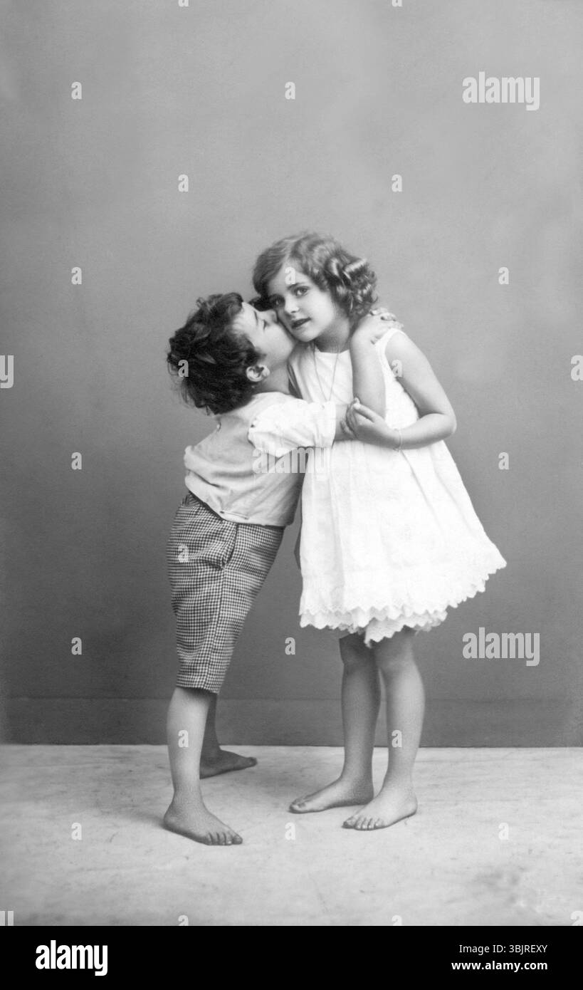 Le premier baiser, années 1930, deux enfants dans une étreinte intime, garçon donne à fille un baiser sur la joue, photo historique Banque D'Images