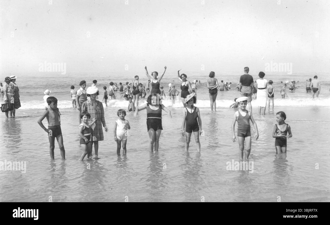 Enfants dans l'eau, années 1920, enfants jouant en eau peu profonde sur la plage sous un ciel dégagé. Une scène estivale joyeuse, photo historique Banque D'Images