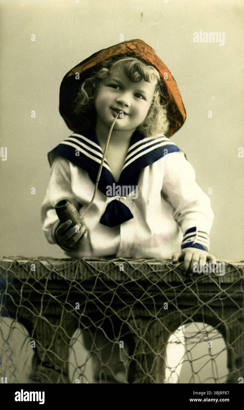 Fille en regard de marin, années 1920, Un garçon en vêtements de marin avec pipe pose souriant, photo historique Banque D'Images