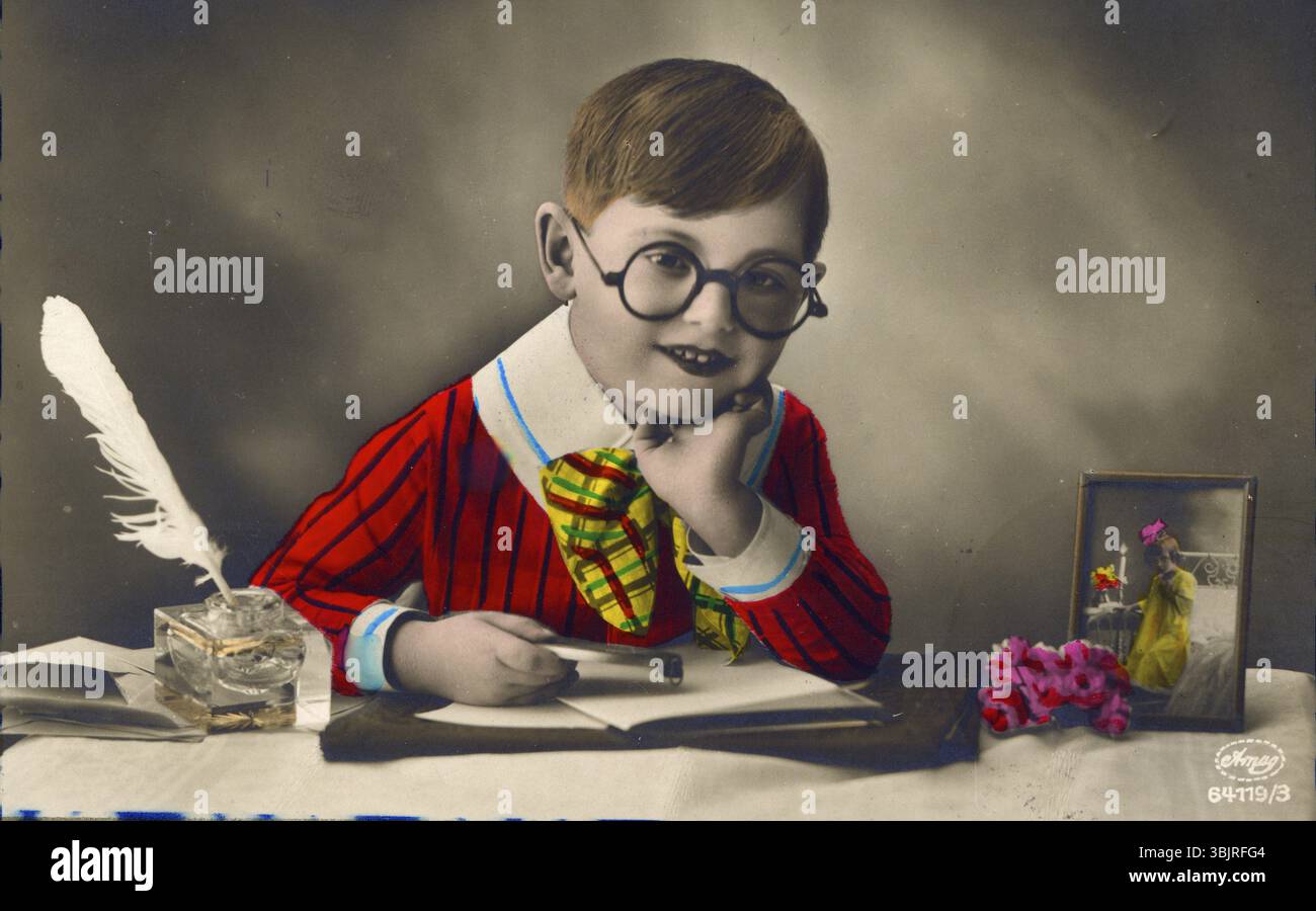 Petit garçon avec des vêtements colorés assis au bureau et écrivant lettre d'amour, années 1920, enfant avec des lunettes dans des vêtements colorés au bureau, avec plume et flow Banque D'Images