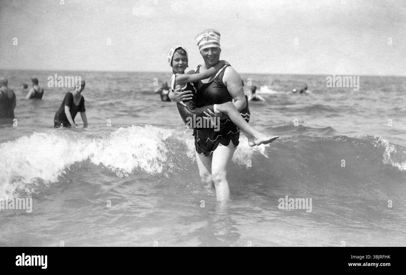 Femme dans l'eau avec un enfant, années 1920, Une femme et un enfant en maillot de bain souriant dans la mer, photo historique Banque D'Images