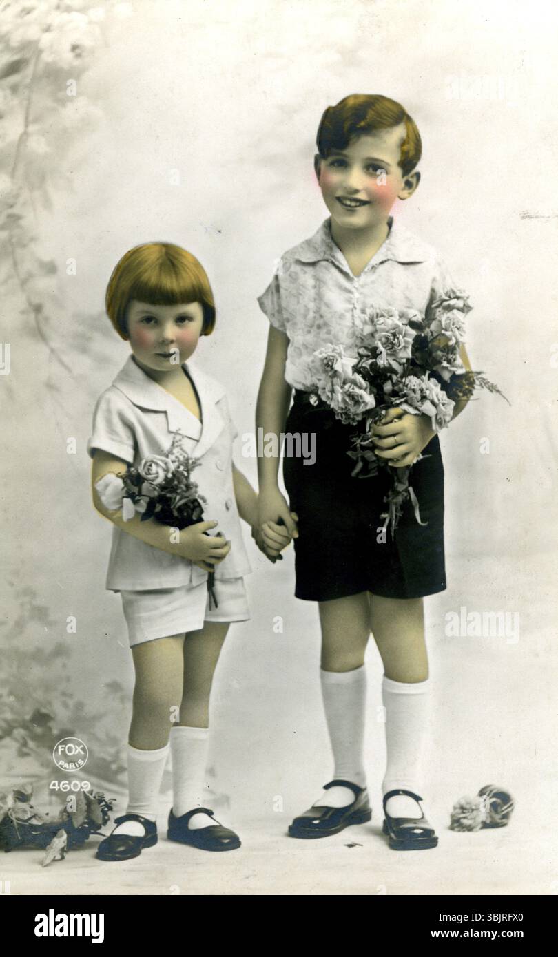 Frère et soeur, 1920 ans, deux enfants dans des vêtements élégants tenant des fleurs, rayonnant de douceur et d'innocence, photo historique Banque D'Images