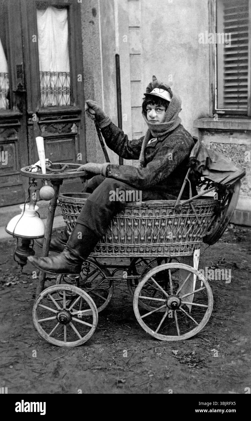 Homme déguisé en poussette, années 1920, Une femme en vêtements anciens conduit un vieux véhicule à quatre roues, photo historique Banque D'Images