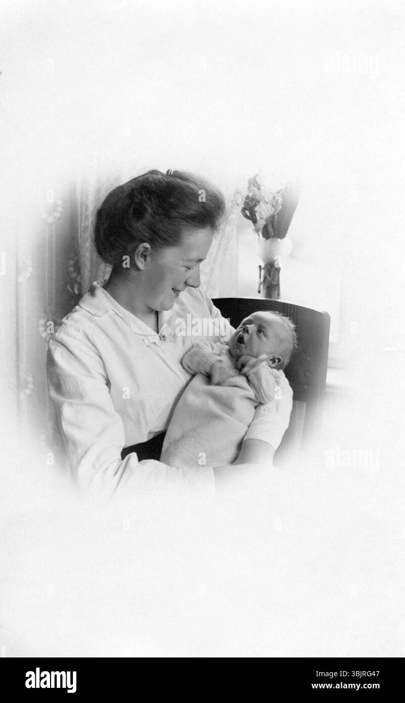 Femme avec bébé dans ses bras, années 1930, Une femme tient amoureusement un bébé dans ses bras, photo historique Banque D'Images