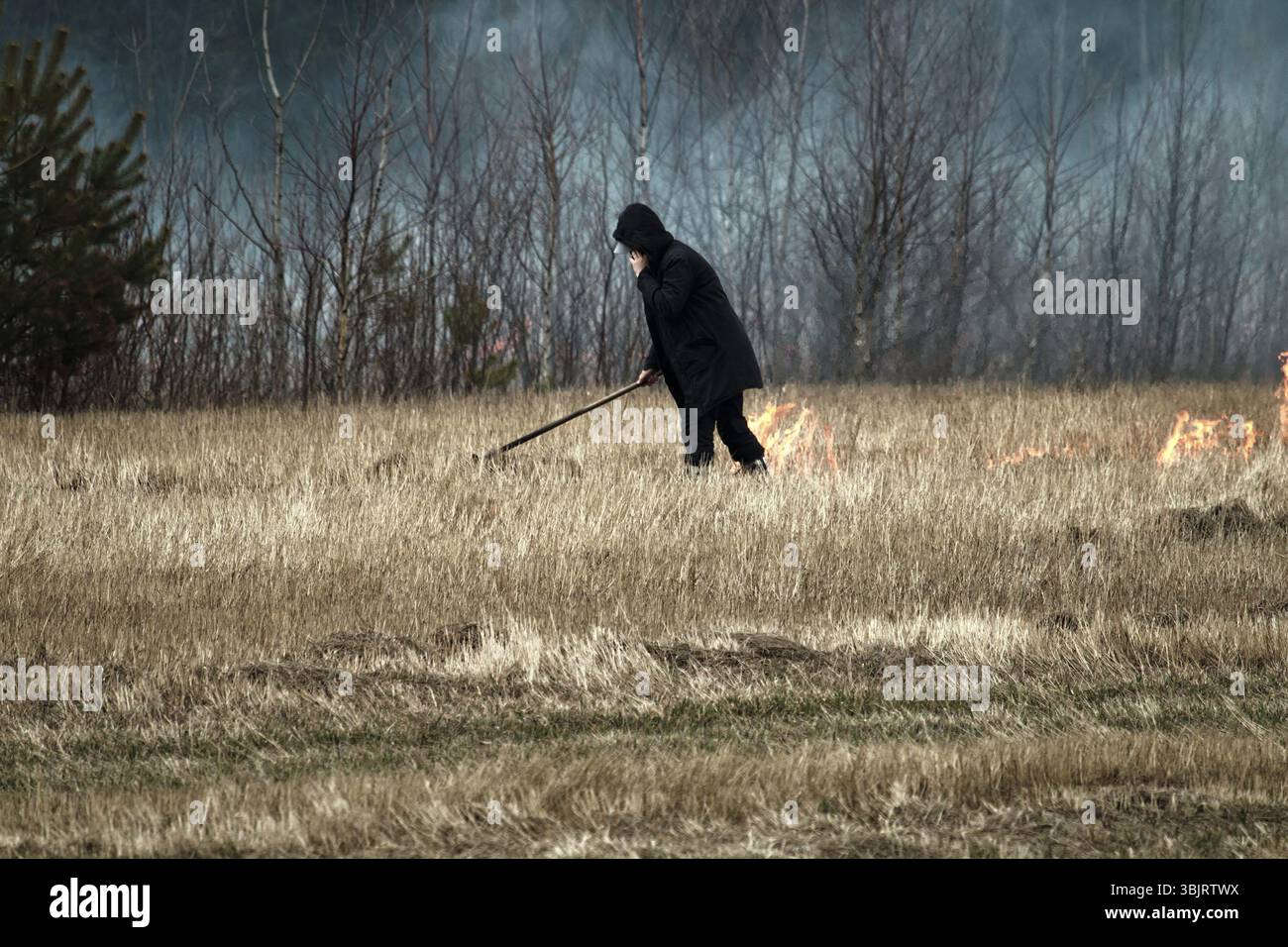 Pyromane sur le terrain. Un terrain en pente et un homme met le feu à l'herbe sèche. Source de vastes incendies sur la Prairie Banque D'Images