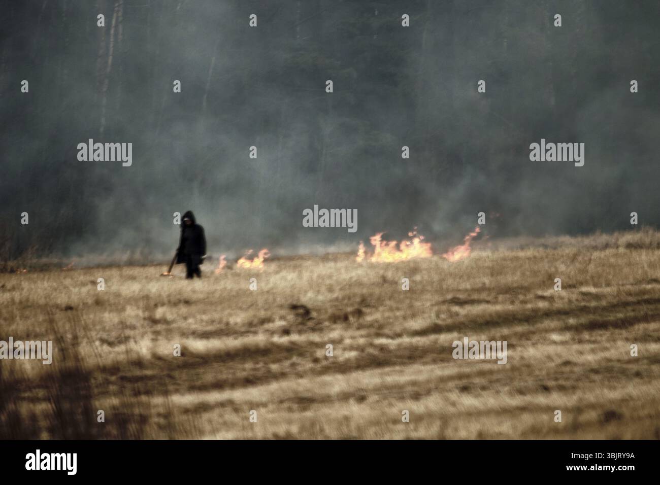 Pyromane sur le terrain. Un terrain en pente et un homme met le feu à l'herbe sèche. Source de vastes incendies sur la Prairie Banque D'Images