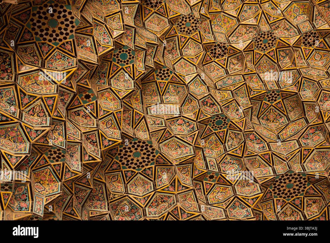 Plafond géométrique orné d'une mosquée à Shiraz, Iran, mettant en valeur l'artisanat persan traditionnel, des couleurs vives et le design islamique. Banque D'Images