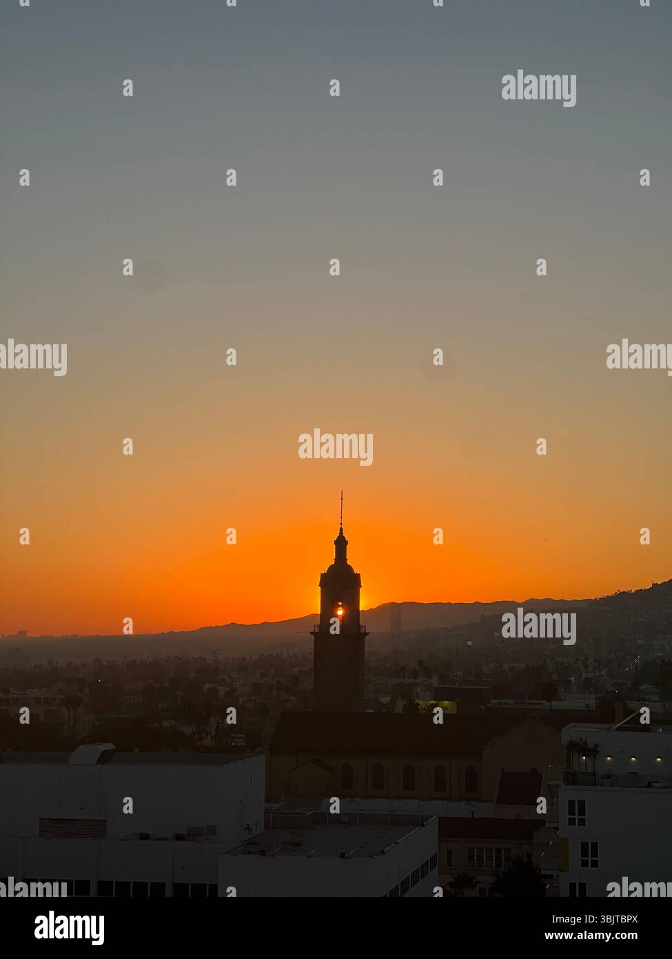 Une vue de la paroisse jésuite du Saint Sacrement à Hollywood, Los Angeles, capturée au coucher du soleil. Le soleil est aligné derrière la tour de l'église. - Image de stock capturée avec un smartphone