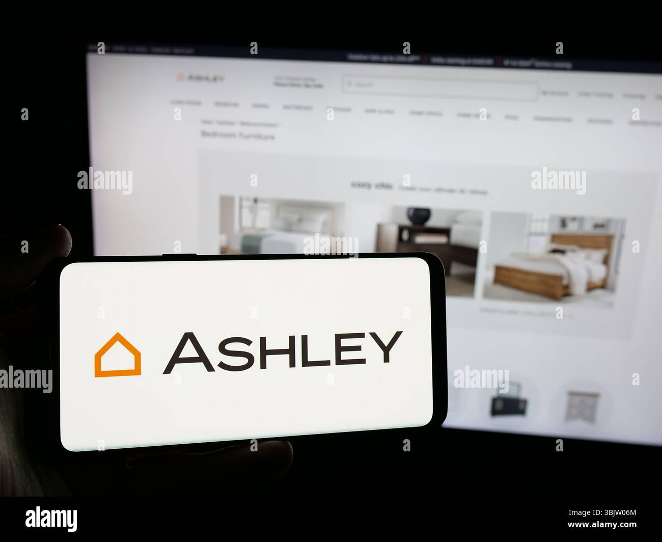 Stuttgart, Allemagne - 2025 : personne tenant un smartphone avec le logo de la société américaine Ashley Furniture Industries Inc. sur l'écran en face du site Web Banque D'Images