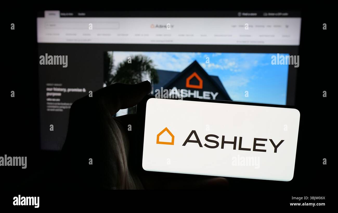 Stuttgart, Allemagne - 2025 : personne tenant un téléphone portable avec le logo de la société américaine Ashley Furniture Industries Inc. sur l'écran devant la page web. Banque D'Images