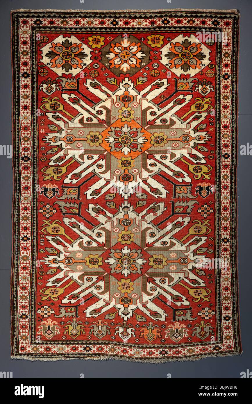 Tapis de laine coloré avec ornement géométrique ethnique traditionnel est sur fond gris. Vue de face, texture de photo d'arrière-plan Banque D'Images