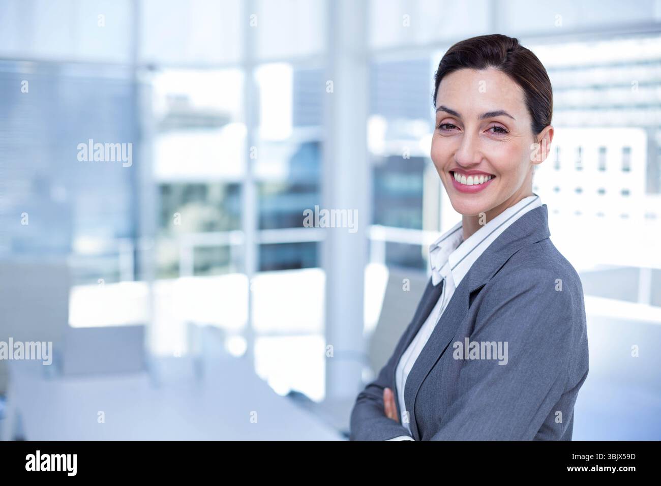 Femme d'affaires debout dans la salle de conférence portant costume près de la table avec vue sur la ville, espace de copie Banque D'Images