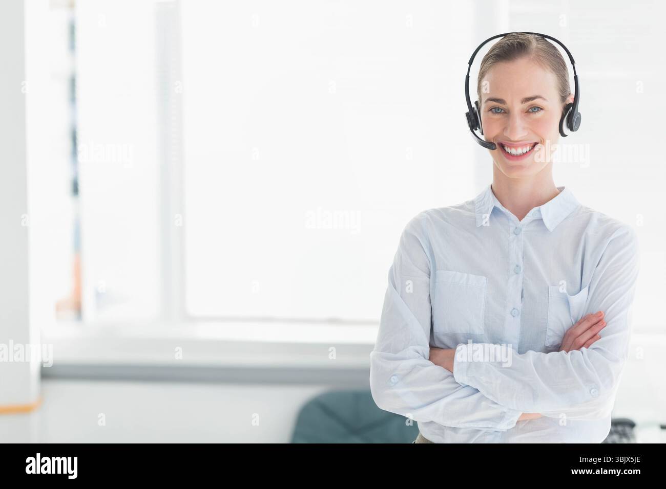 Micro-casque du service clientèle reposant sur une chemise bleu clair drapée sur une chaise pivotante près de la fenêtre lumineuse Banque D'Images