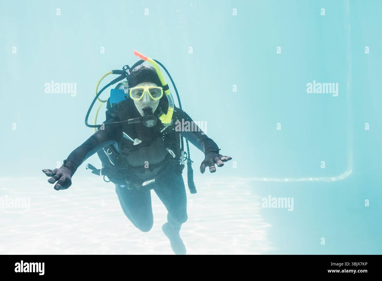 Plongeur sous-marin pratiquant sous l'eau dans une piscine claire, portant l'équipement complet et un masque jaune près du sol carrelé Banque D'Images Plongeur sous-marin pratiquant sous l'eau dans une piscine claire, portant l'équipement complet et un masque jaune près du sol carrelé Banque D'Images