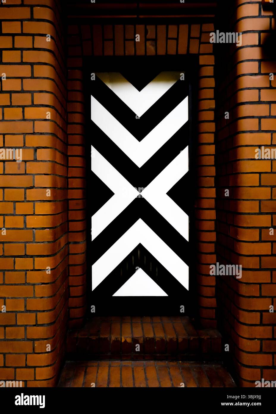 Gros plan d'un mur de briques avec une porte en noir et blanc. Banque D'Images