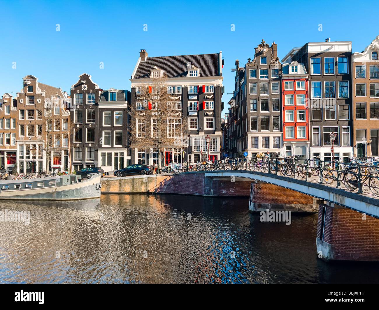 Vue rapprochée du canal d'Amsterdam avec des vélos sur le pont et les maisons hollandaises Banque D'Images