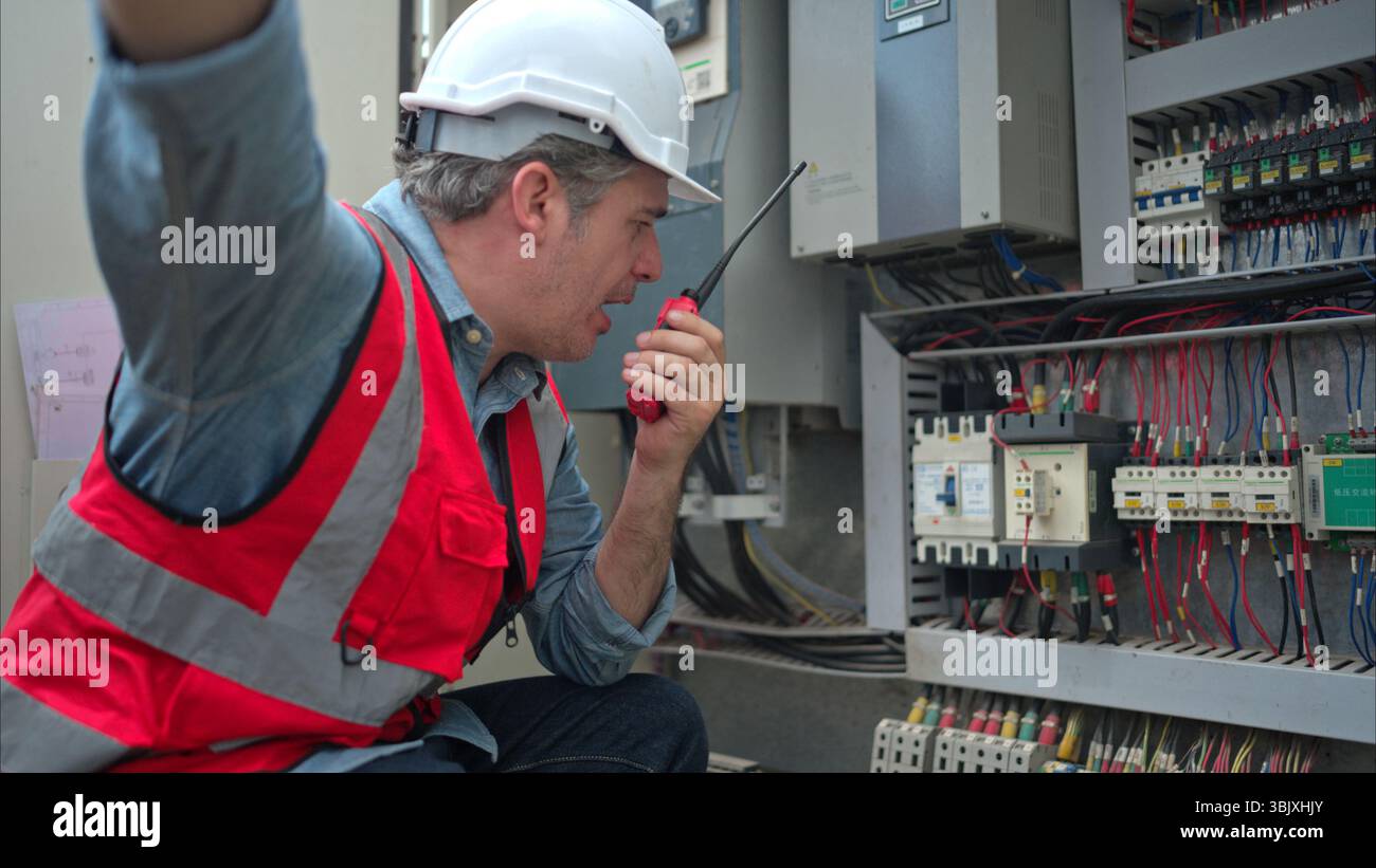 L'ingénieur électricien inspecte le tableau de commande électrique d'une grue avant de la mettre en service sur un chantier de construction Banque D'Images