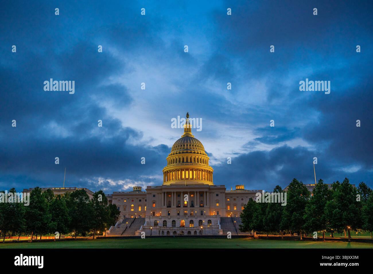 Le bâtiment du Capitole des États-Unis brille d'une lumière jaune chaude à l'aube à Washington, DC, debout contre un ciel bleu profond dans le calme de tôt le matin. Banque D'Images