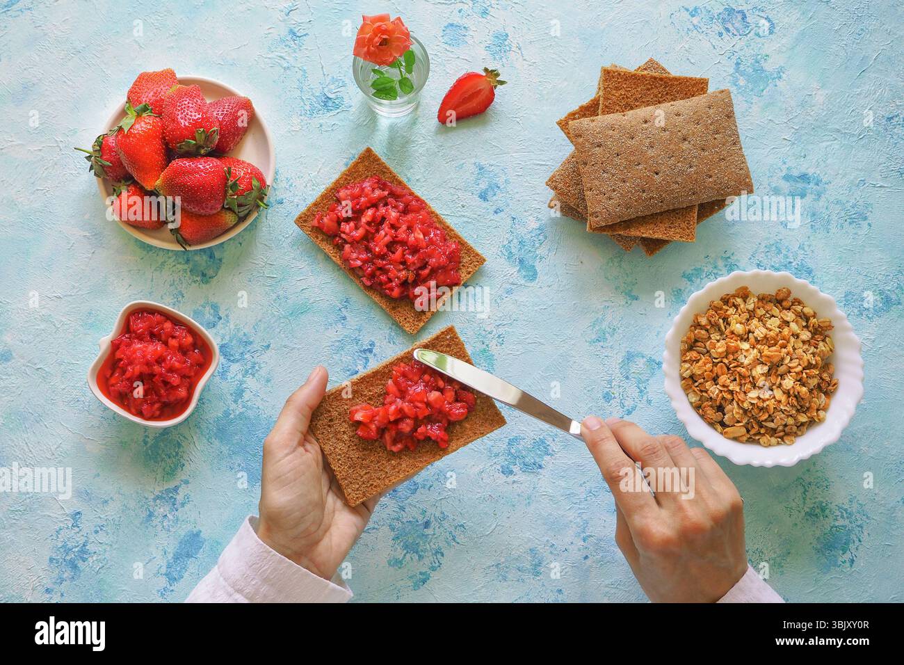 Seigle croustillant avec confiture de fraises. Toast aux fraises sur pain de seigle. Petit déjeuner sucré végétarien sur fond bleu Banque D'Images