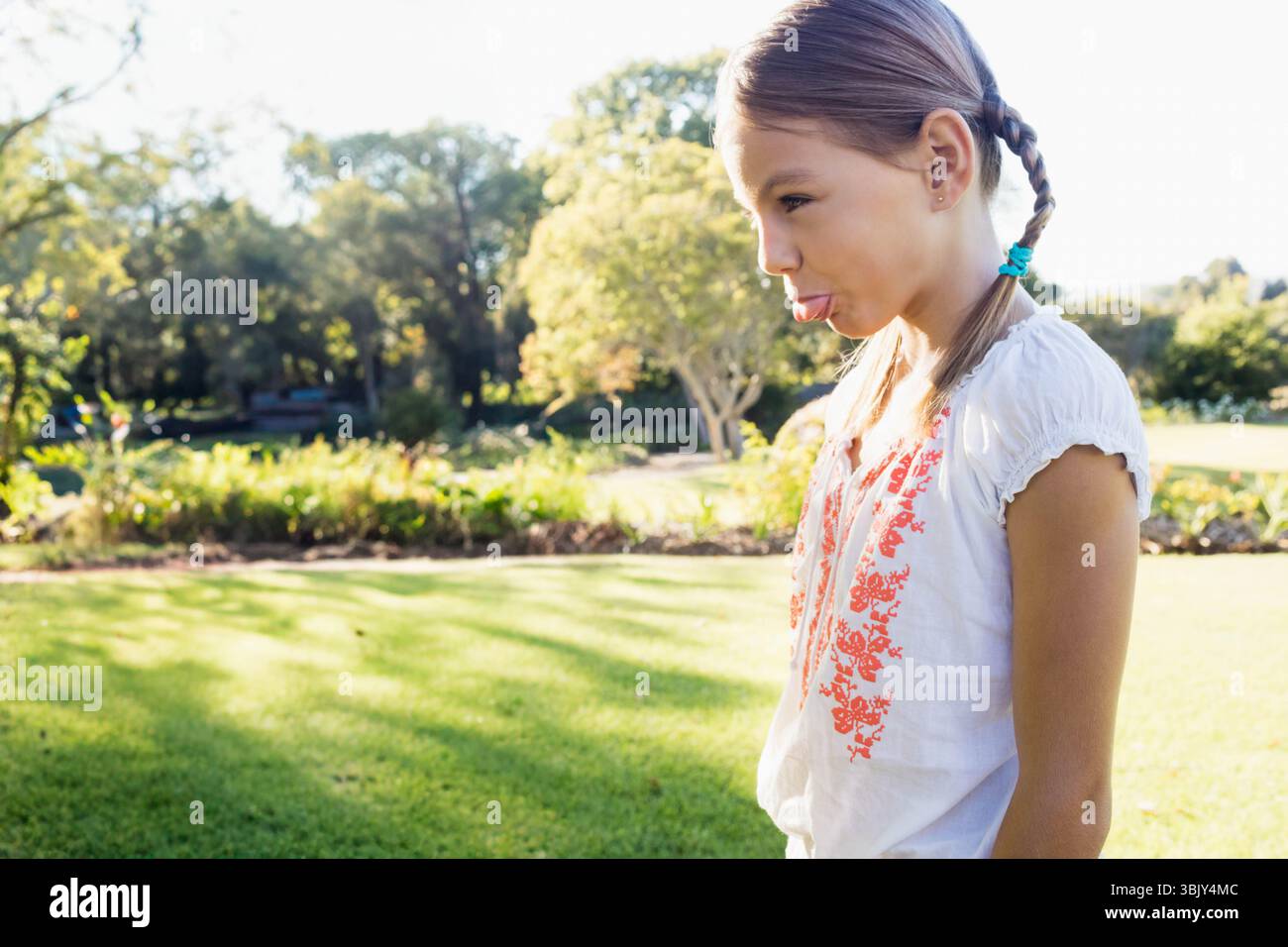 Fille sortant de la langue portant chemisier brodé sur la pelouse bien entretenue dans le parc, copier l'espace Banque D'Images