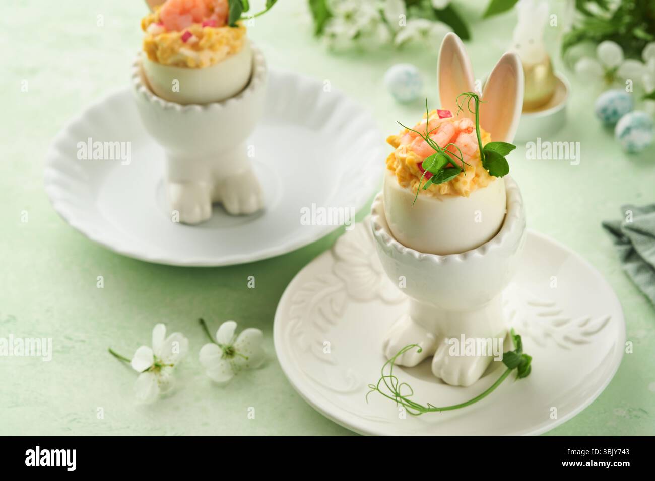 Œufs farcis ou dévorés avec jaune, crevettes, pois microverts avec paprika en forme de lapin support pour la table de pâques décorer frais c Banque D'Images