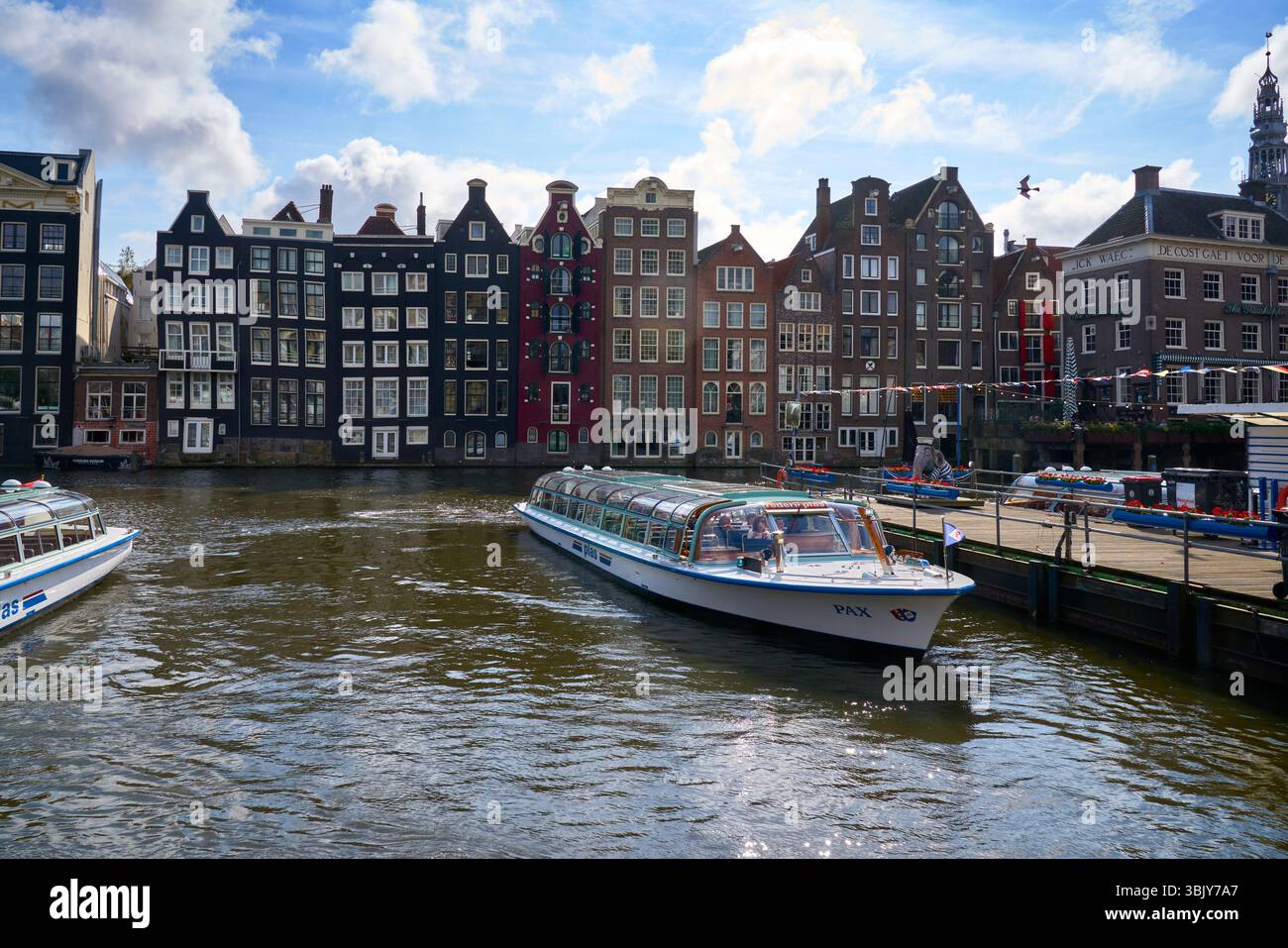 Damrak Dancing Houses Amsterdam pays-Bas. Les célèbres maisons de danse Damrak d'Amsterdam et les bateaux touristiques sur le canal par une journée ensoleillée. Banque D'Images